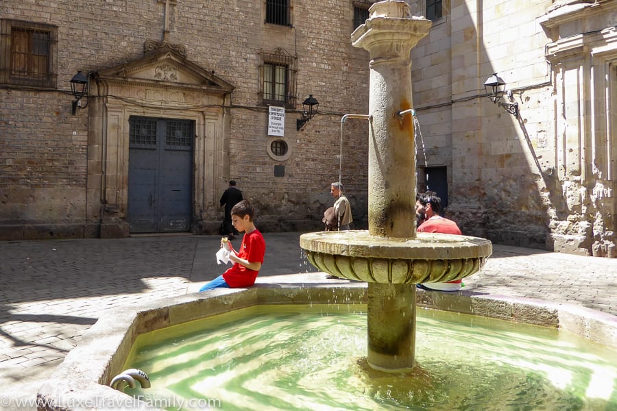 A fountain and a boy eating lunch in Placa de Sant Philip Neri, Barcelona