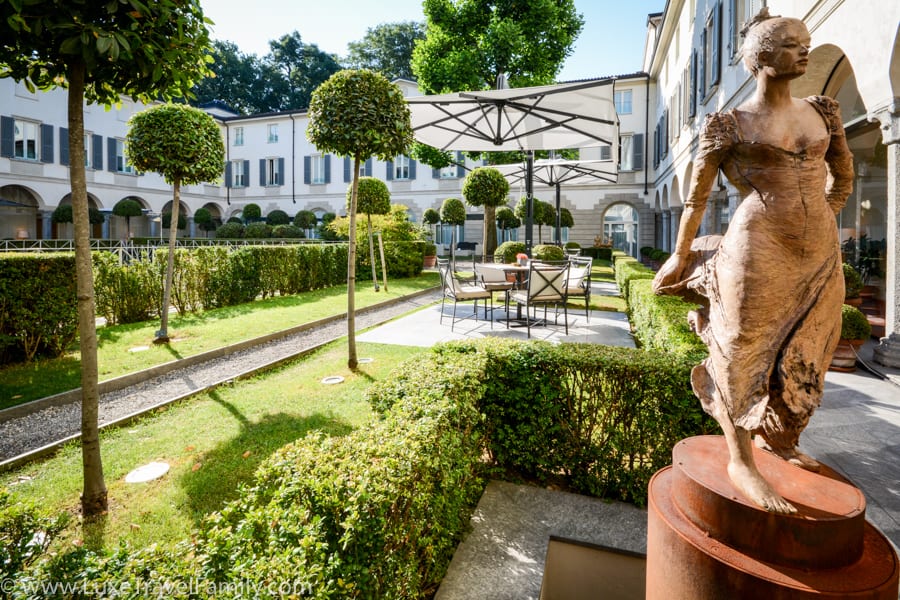 Statue of a woman, box hedge, topiaries and sitting areas in the courtyard at Four Seasons Hotel Milano