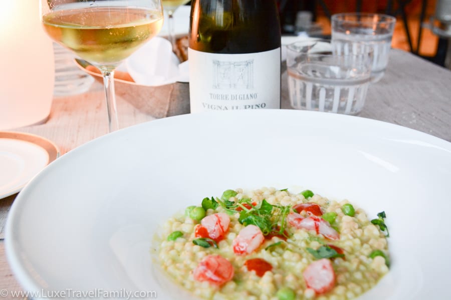 A bowl of Sardinian fregula pasta, glass of white wine and a bottle of wine at the Four Seasons Milano